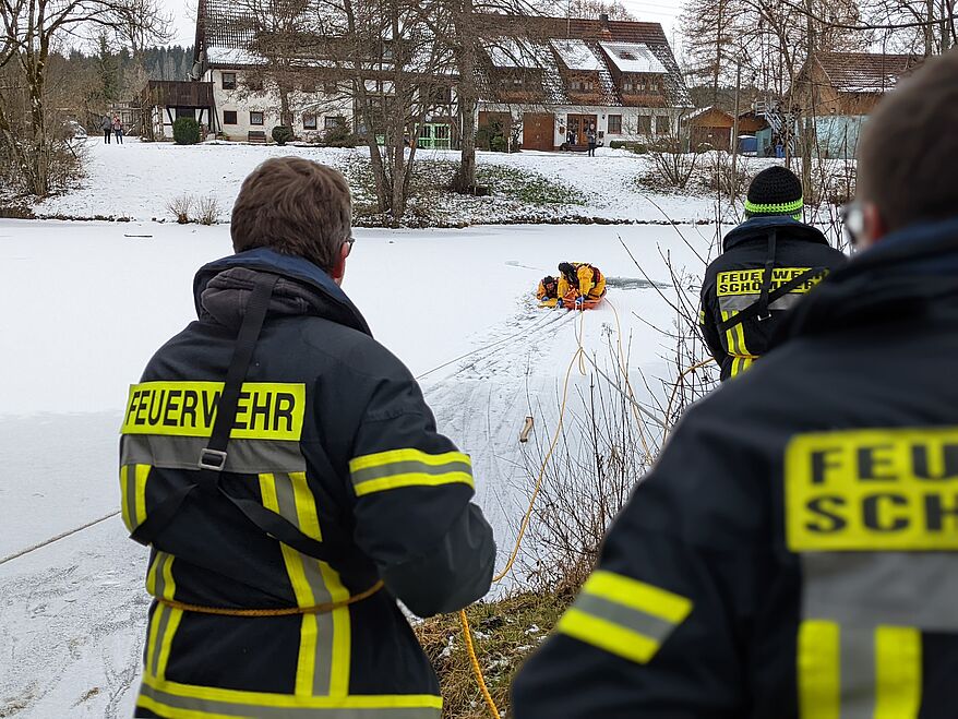 Retter und eingebrochene Person werden an Land gezogen